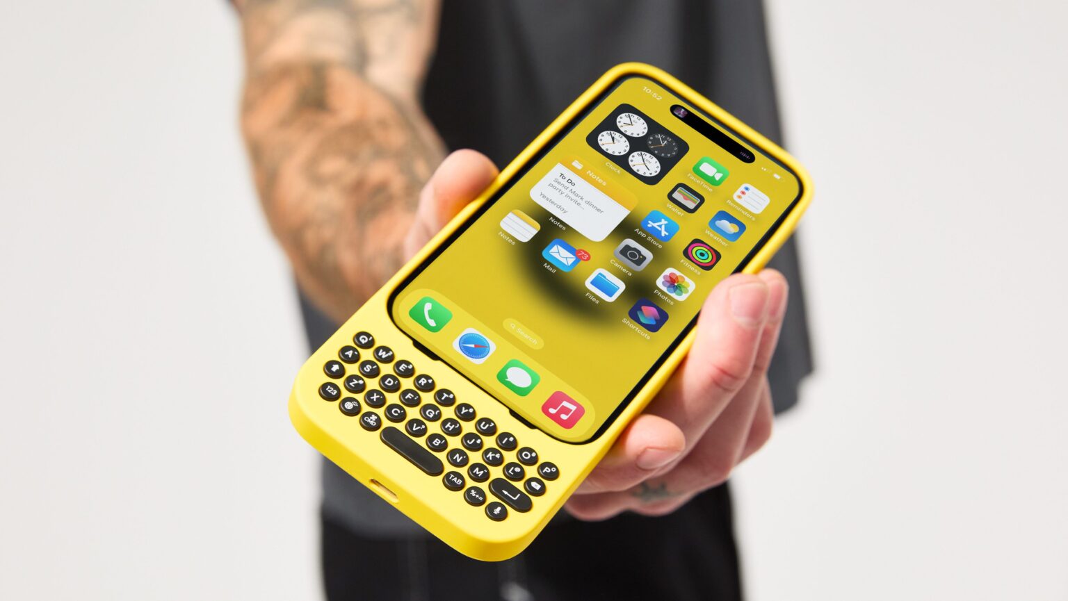 Pessoa entregando um iPhone com uma capinha amarela com teclado